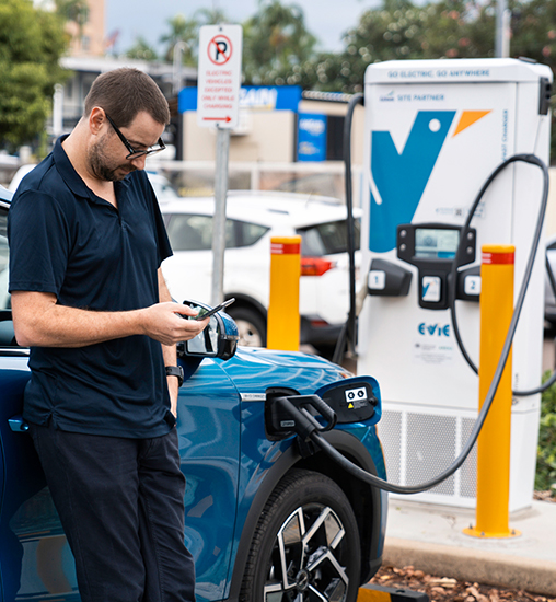 Man charging his Electric Vehicle (EV) at a charging station.