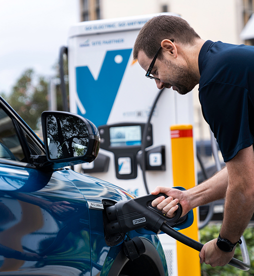 Man charging his Electric Vehicle (EV) at a charging station.