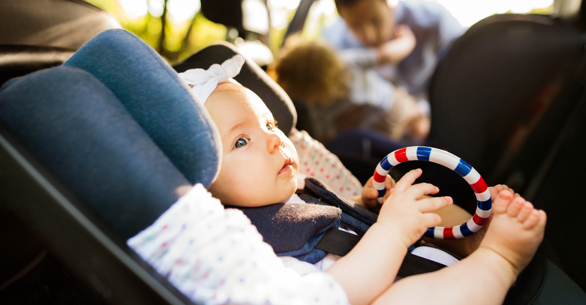 Baby in a car seat playing with a rattle