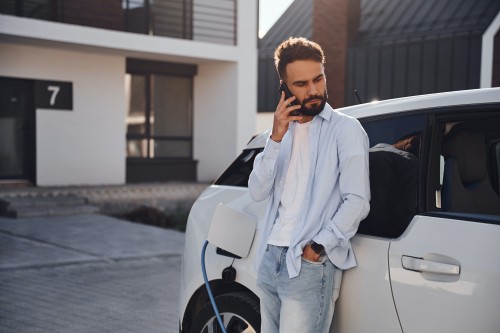 Man charging EV and talking on the phone