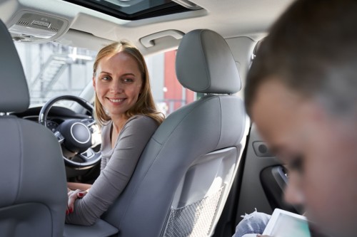 Woman smiling in a car looking back at her children in the back seat