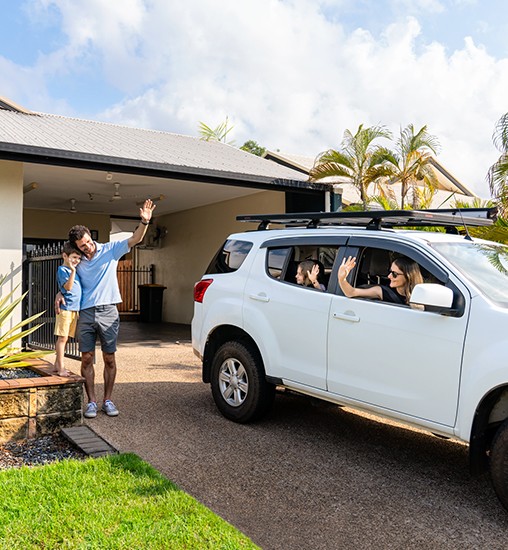 Dad and son waiving to mum and daughter leaving home in a car.